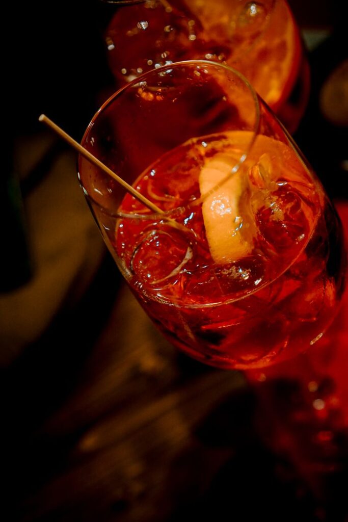 pexels-photo-10755776 A vibrant Aperol spritz cocktail in a glass with an orange slice, photographed in a Venice bar.