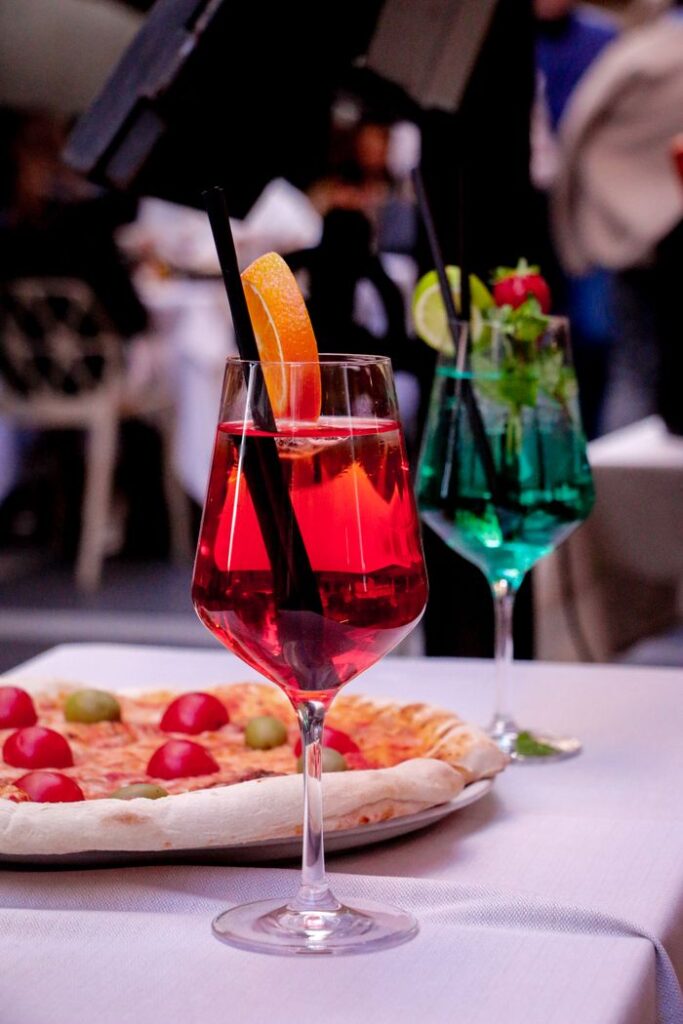 pexels-photo-29655808 Colorful cocktails with pizza on an outdoor table, perfect for a refreshing dining experience.
